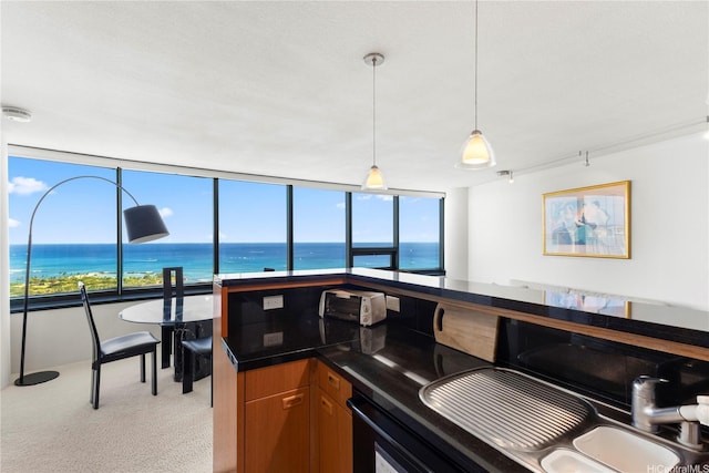1330 Ala Moana Blvd Unit 3305, Honolulu, HI 96814 - kitchen featuring dark countertops, a water view, decorative light fixtures, and light carpet