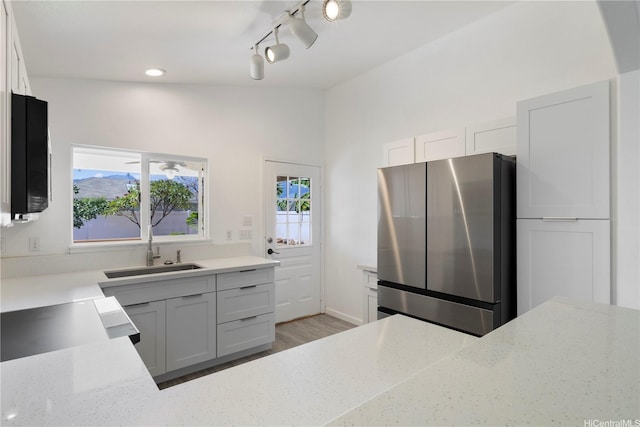 87-1106 Oheohe St, Waianae, HI 96792 - kitchen with freestanding refrigerator, rail lighting, light wood-type flooring, light stone countertops, and white cabinetry