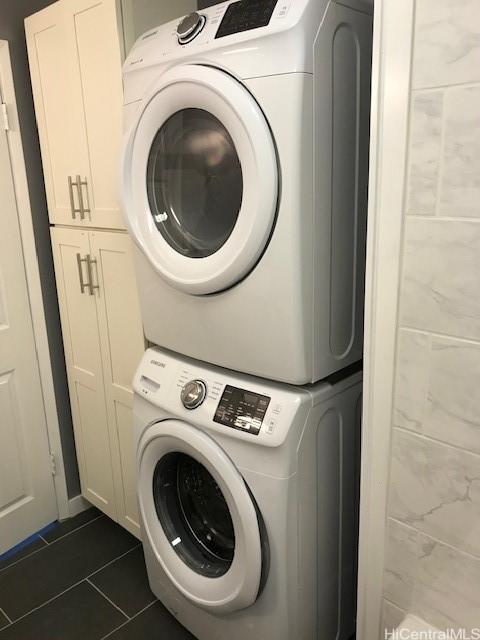 775 Kinalau Pl Unit 1204, Honolulu, HI 96813 - laundry area with stacked washer / drying machine, cabinet space, and dark tile patterned flooring