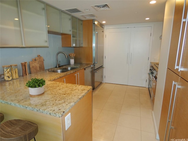 1177 Queen St Unit 3405, Honolulu, HI 96814 - kitchen with appliances with stainless steel finishes, a peninsula, light stone countertops, a breakfast bar, and light tile patterned floors