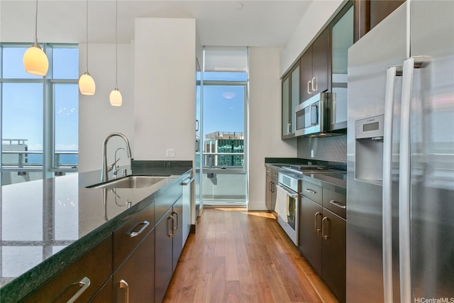 1189 Waimanu St Unit 4301, Honolulu, HI 96814 - kitchen with appliances with stainless steel finishes, wood finished floors, dark stone countertops, decorative backsplash, and decorative light fixtures