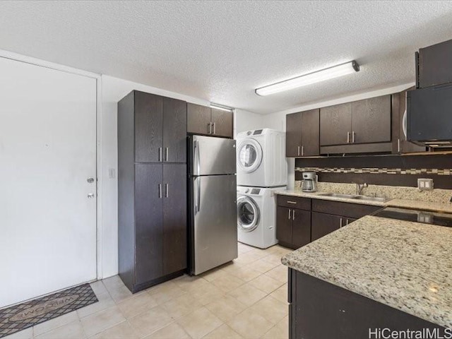 95-2055 Waikalani Pl Unit B404, Mililani, HI 96789 - kitchen with stacked washer / drying machine, freestanding refrigerator, dark brown cabinets, a textured ceiling, and light stone counters