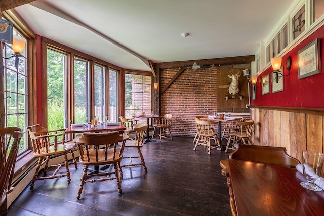 dining space with ceiling fan, a baseboard heating unit, brick wall, and dark wood-type flooring