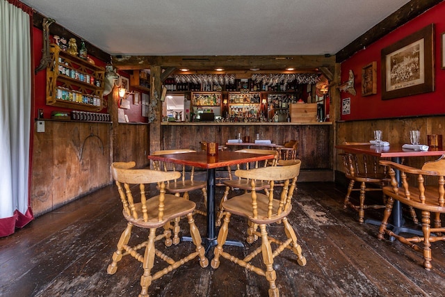 bar with beam ceiling, dark wood-type flooring, and a textured ceiling