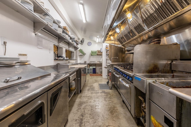 kitchen featuring stainless steel counters, concrete floors, and custom range hood