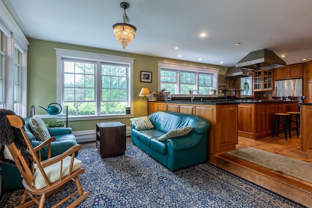 tiled living room with a notable chandelier, plenty of natural light, baseboard heating, and sink