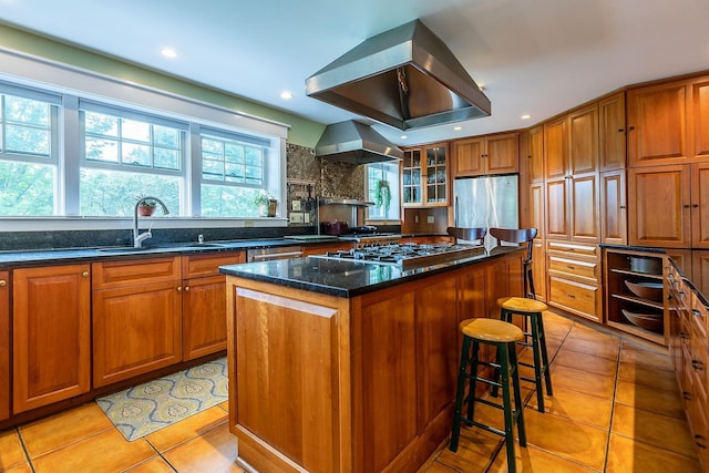 kitchen featuring a center island, wall chimney range hood, light tile floors, a kitchen breakfast bar, and island exhaust hood