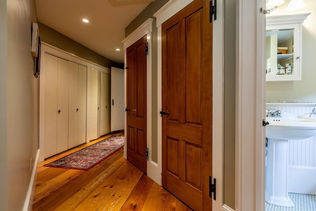 hallway with light wood-type flooring and sink