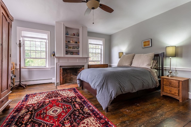 bedroom with ceiling fan, dark hardwood / wood-style floors, and a baseboard heating unit