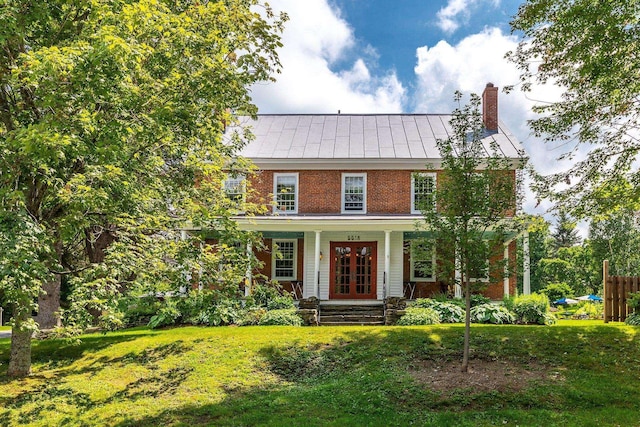 colonial home featuring a front yard and covered porch