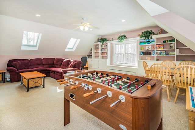 game room featuring vaulted ceiling with skylight, a baseboard heating unit, ceiling fan, and light colored carpet