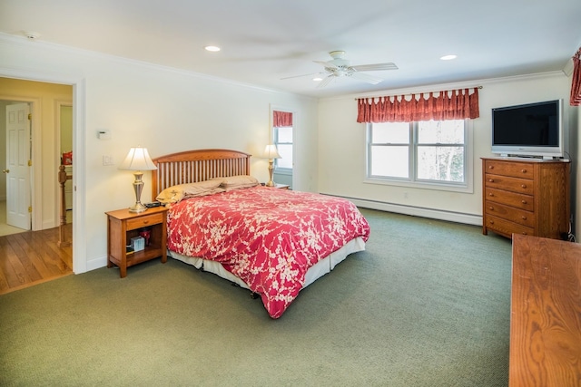 bedroom featuring baseboard heating, dark colored carpet, ceiling fan, and ornamental molding