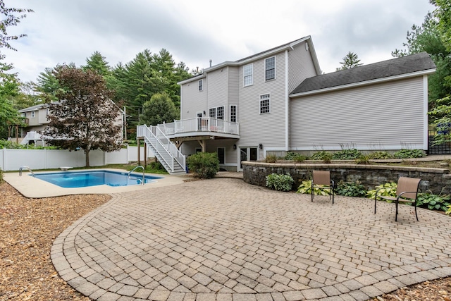 view of swimming pool with a wooden deck, a diving board, and a patio