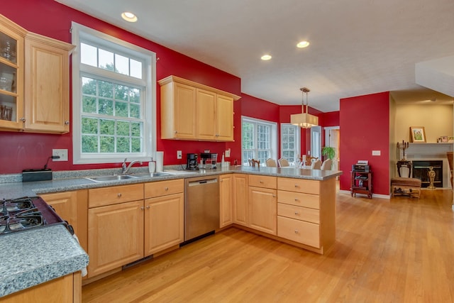 kitchen featuring stainless steel dishwasher, light hardwood / wood-style floors, decorative light fixtures, sink, and kitchen peninsula