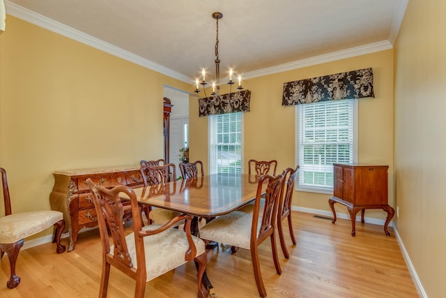 dining space with light wood-type flooring, crown molding, and a chandelier