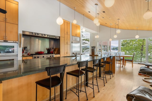 kitchen with sink, hanging light fixtures, light wood-type flooring, appliances with stainless steel finishes, and wood ceiling