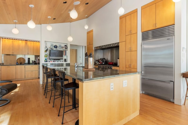 kitchen with stainless steel built in refrigerator, a large island with sink, decorative light fixtures, and wood ceiling