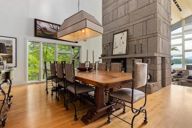 dining room with light hardwood / wood-style floors, a towering ceiling, and a fireplace