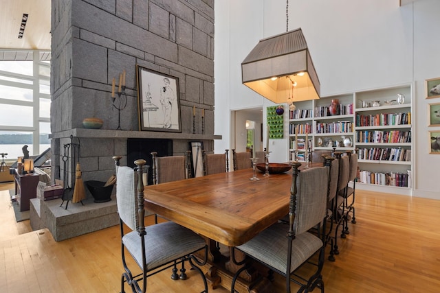 dining space with built in features, a towering ceiling, and light hardwood / wood-style flooring