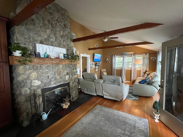 living room featuring dark hardwood / wood-style floors, ceiling fan, vaulted ceiling with beams, and a stone fireplace