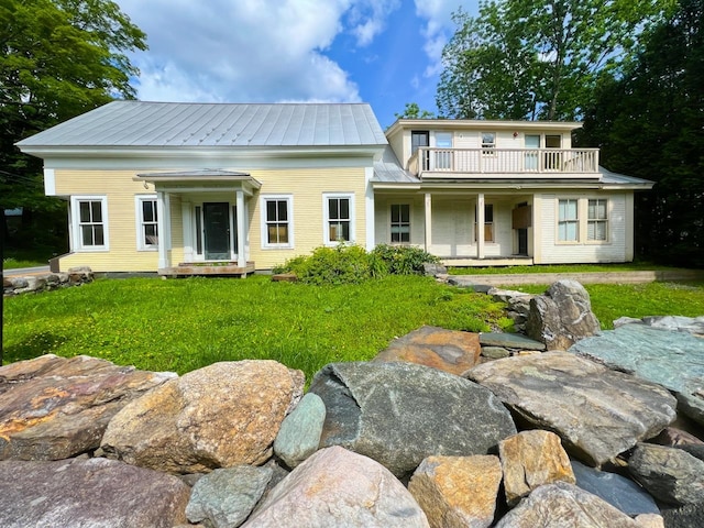 rear view of property featuring a balcony and a yard