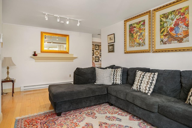 living room with baseboard heating, light hardwood / wood-style flooring, rail lighting, and crown molding