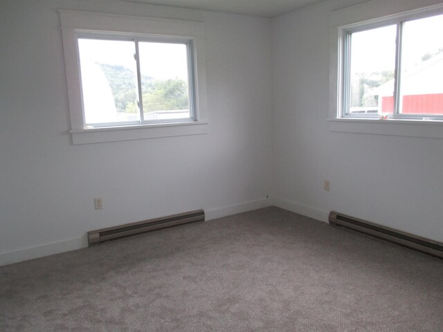 unfurnished room featuring baseboard heating, carpet floors, and a healthy amount of sunlight