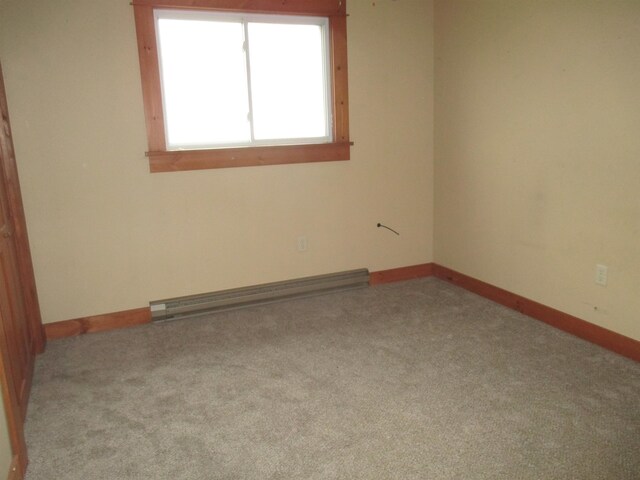 unfurnished room with baseboard heating and carpet