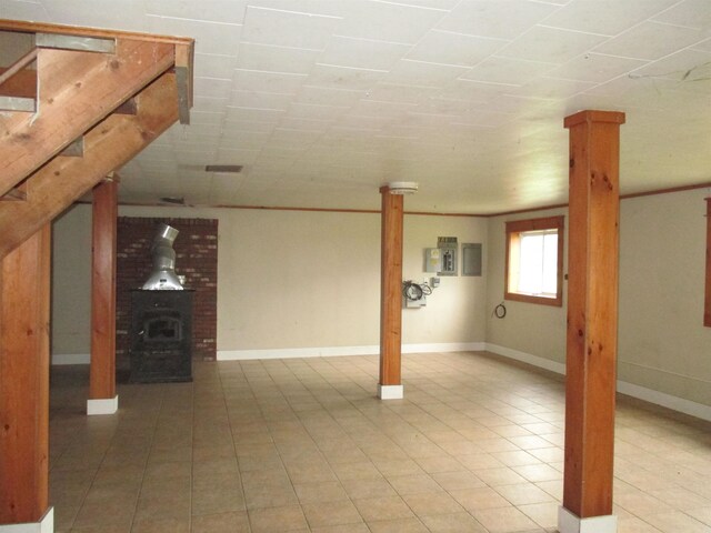 basement featuring a wood stove, brick wall, and light tile floors