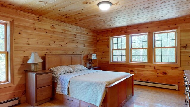 bedroom with light hardwood / wood-style floors, multiple windows, and baseboard heating