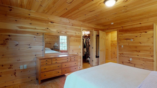 bedroom with wood walls, a spacious closet, hardwood / wood-style floors, and a closet