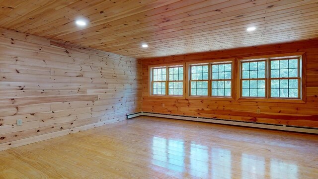 empty room with light hardwood / wood-style flooring, a healthy amount of sunlight, a baseboard radiator, and wooden ceiling