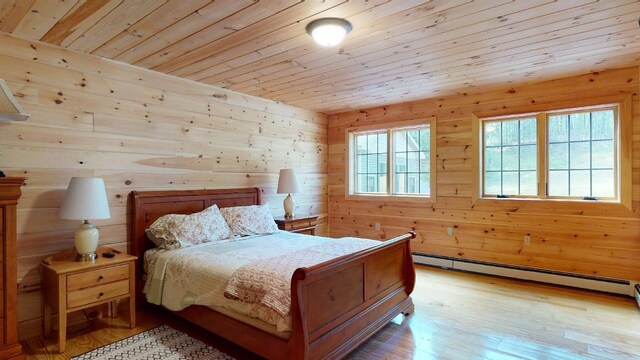 bedroom featuring baseboard heating, wood walls, wood ceiling, and light wood-type flooring