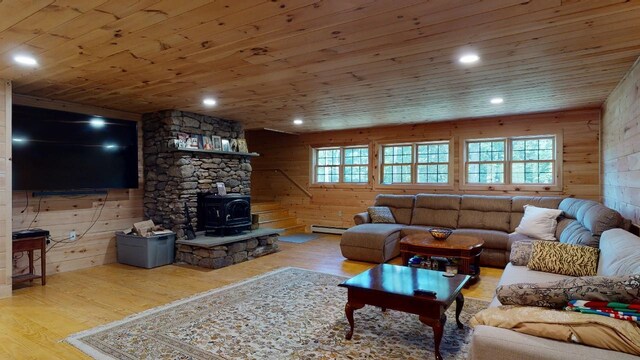 living room featuring wooden ceiling, wooden walls, light hardwood / wood-style floors, and a wood stove