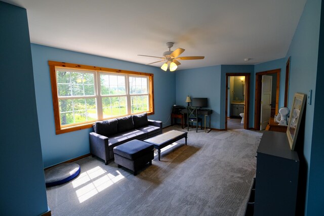 carpeted living area with baseboards and a ceiling fan
