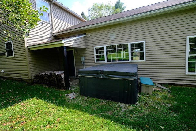 back of house featuring a lawn and a hot tub