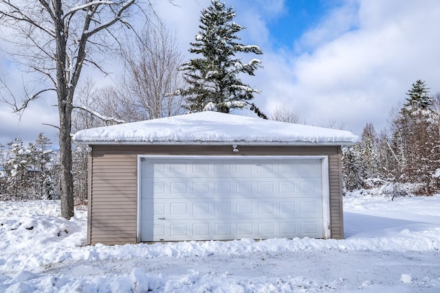 snow covered garage with a detached garage
