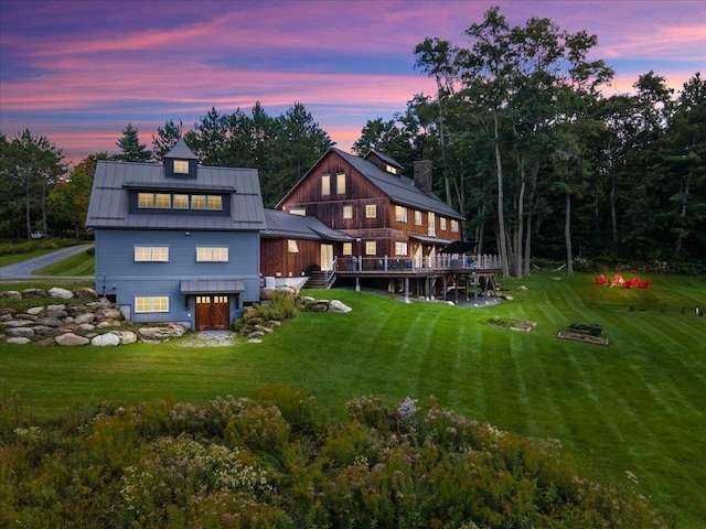 back house at dusk featuring a lawn