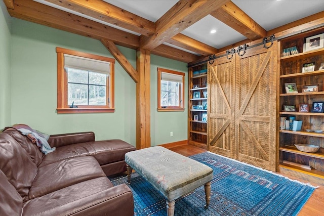 living room featuring a wealth of natural light, dark wood-type flooring, beamed ceiling, and a barn door