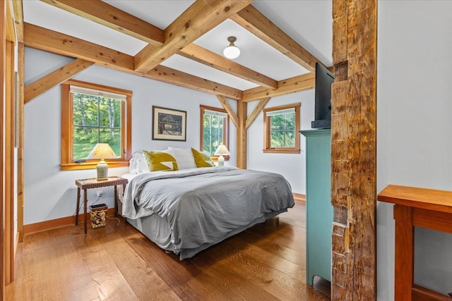 bedroom with beamed ceiling, dark wood-type flooring, and multiple windows