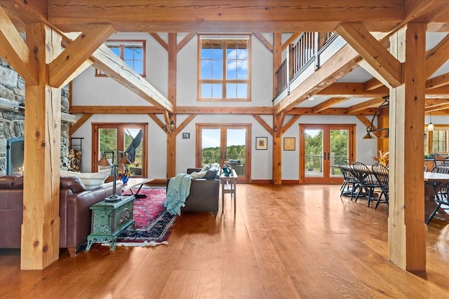 living room with a fireplace, a towering ceiling, a healthy amount of sunlight, and light hardwood / wood-style flooring