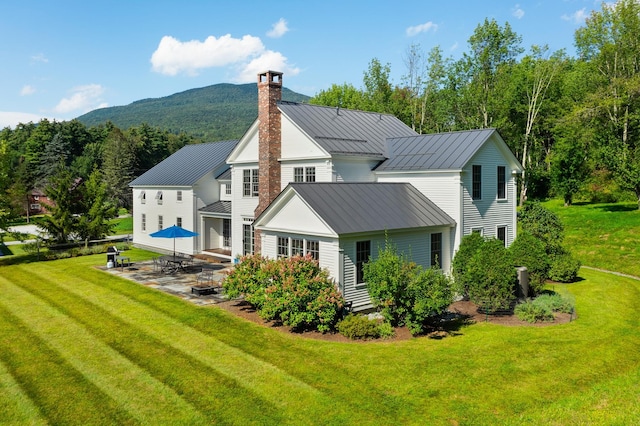 rear view of property featuring a yard, a mountain view, and a patio