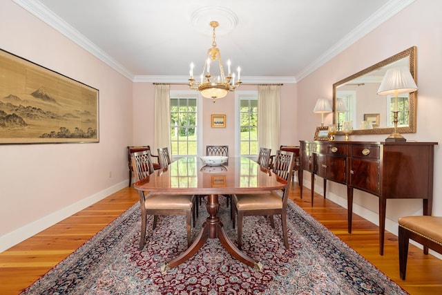 dining area featuring ornamental molding, an inviting chandelier, and light hardwood / wood-style flooring