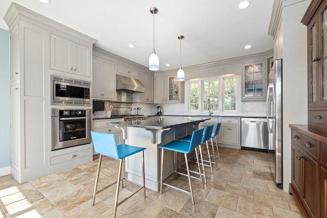 kitchen with a kitchen island, appliances with stainless steel finishes, a breakfast bar, ventilation hood, and sink