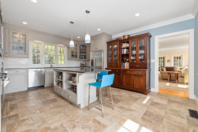 kitchen featuring stainless steel appliances, hanging light fixtures, gray cabinets, and a kitchen bar