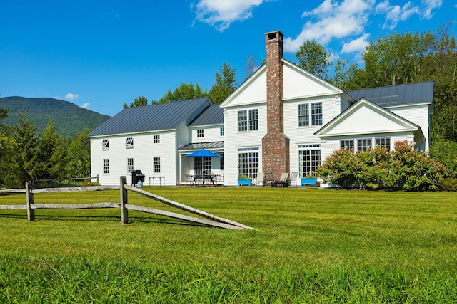 rear view of house with a mountain view and a lawn