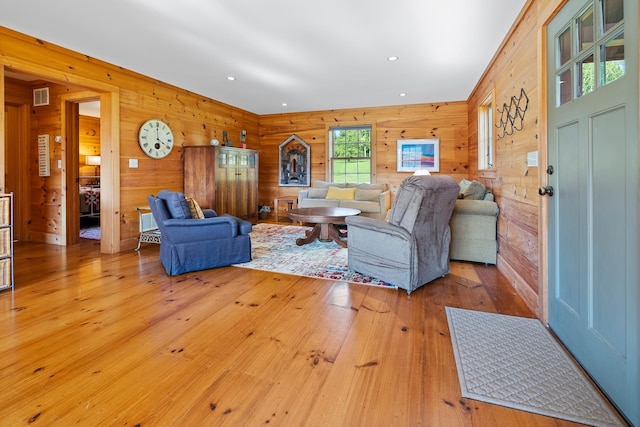 living room with wooden walls and light hardwood / wood-style flooring