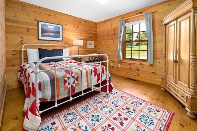 bedroom with wood-type flooring and wood walls