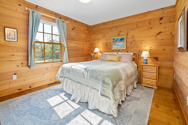 bedroom featuring wooden walls and light hardwood / wood-style floors