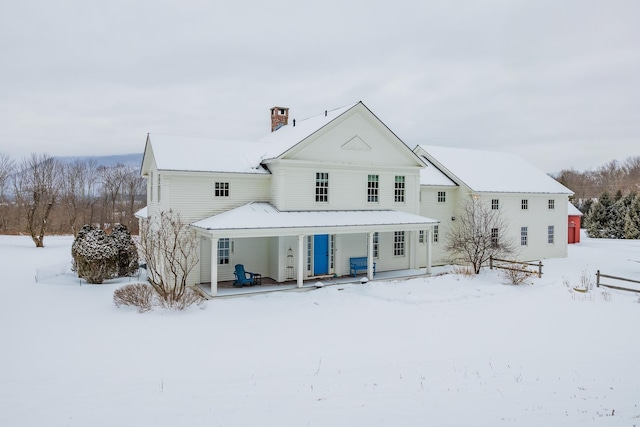 snow covered rear of property with a porch